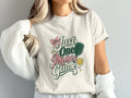 Cream t-shirt with text "Just One More Game", pickleball paddle and ball.