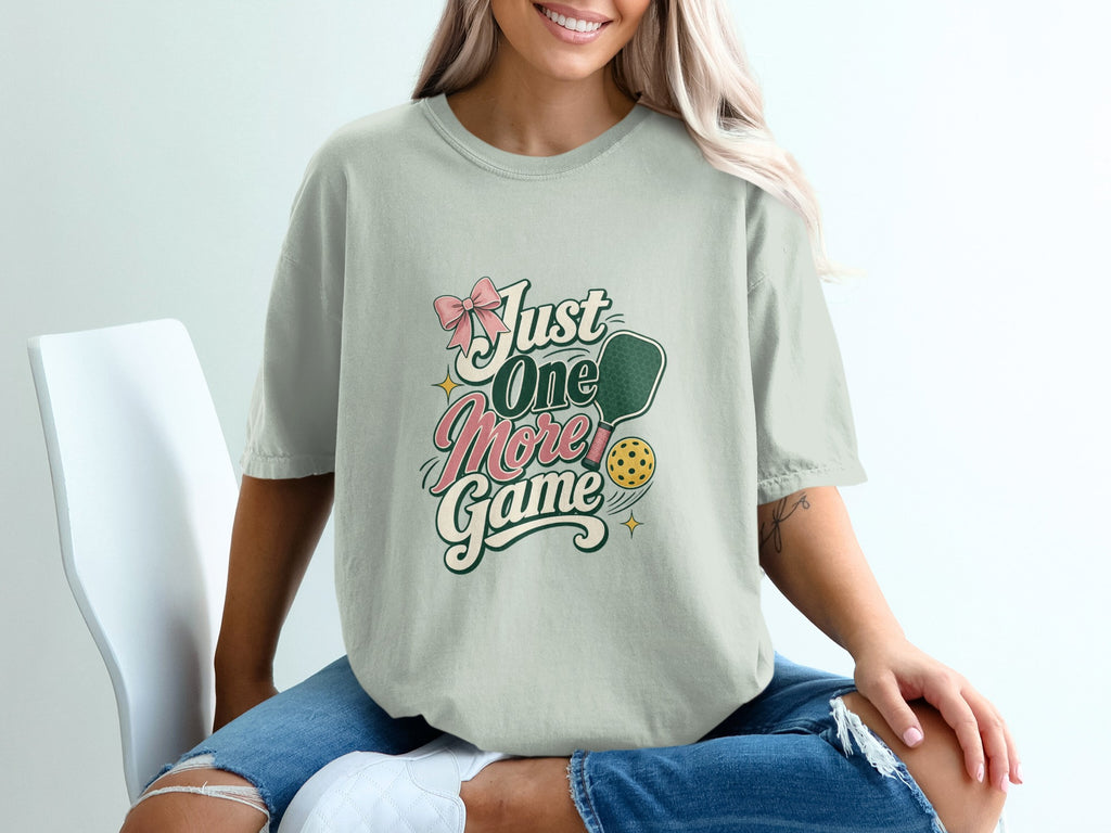 T-shirt with "Just One More Game" pickleball graphic and pink bow.