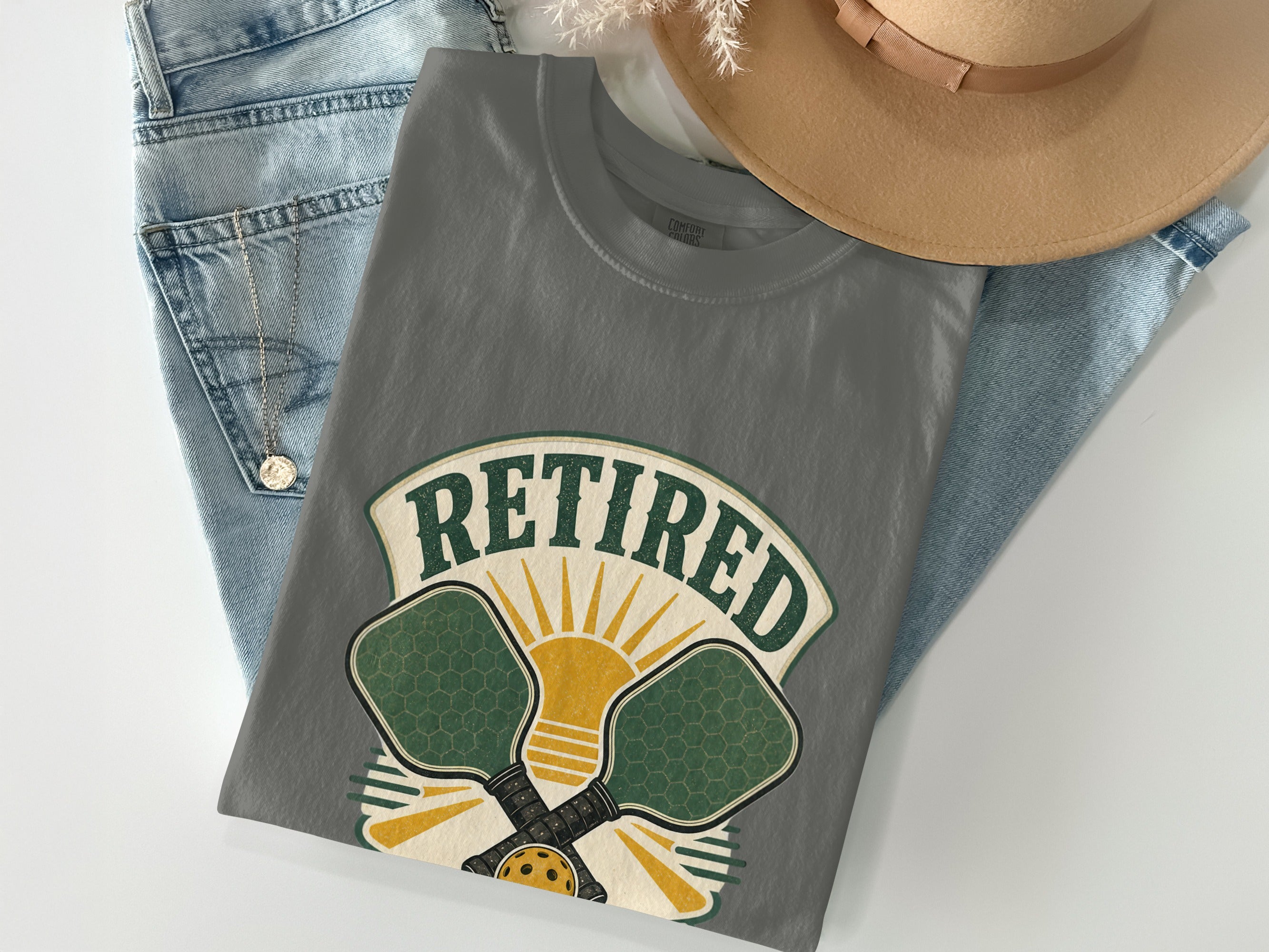 Gray t-shirt with "Retired" text, pickleball paddles, and sun graphic.