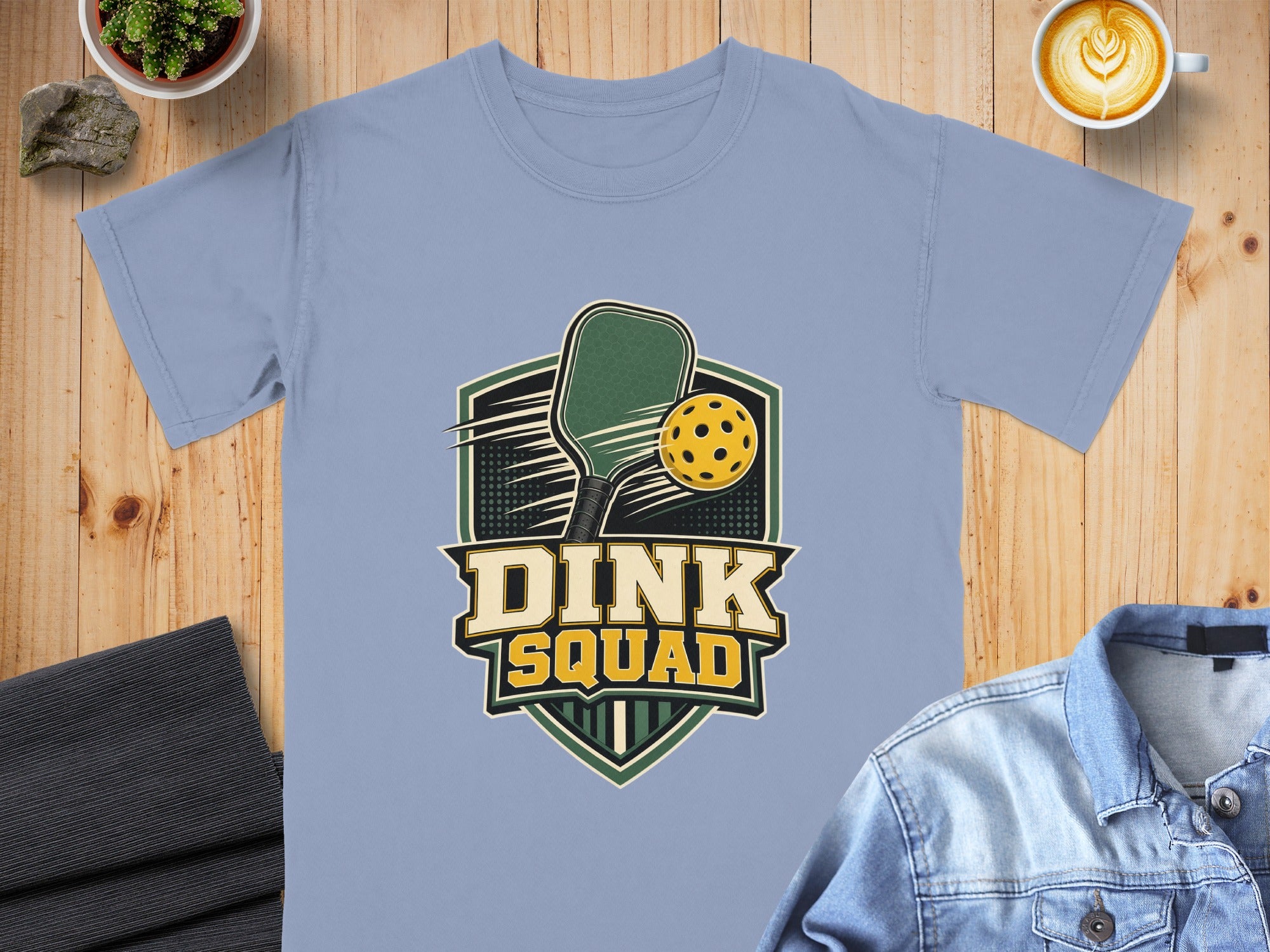 Light blue t-shirt with "Dink Squad" pickleball graphic and superimposed items.