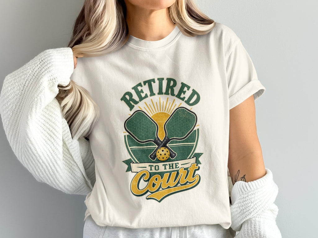 White t-shirt with "Retired to the Court" text and pickleball gear graphic.