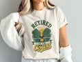White t-shirt with "Retired to the Court" text and pickleball gear graphic.