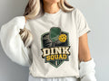 White t-shirt with "DINK SQUAD" graphic featuring pickleball paddle and ball.